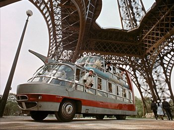 Movie still from “Zazie dans le Métro” (1960), directed by Louis Malle – An old bus is parked in front of the eiffel tower in paris; Wide shot, Low angle