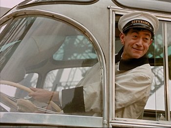 Movie still from “Zazie dans le Métro” (1960), directed by Louis Malle – A man wearing a hat sitting in the driver's seat of a bus; Close Up shot, Low angle