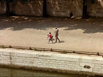 Movie still from “Zazie dans le Métro” (1960), directed by Louis Malle – A man and a boy walking down a sidewalk; Extreme Wide shot, High angle