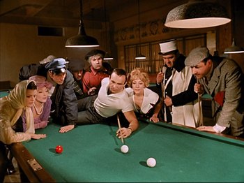 Movie still from “Zazie dans le Métro” (1960), directed by Louis Malle – A group of people gathered around a billiards table; Wide shot, High angle