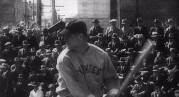 Movie still from “Zelig” (1983), directed by Woody Allen – A baseball player is swinging a bat in front of a group of people; Medium shot, Low angle