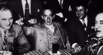 Movie still from “Zelig” (1983), directed by Woody Allen – An old black and white photo of a man sitting at a table; Medium shot, High angle