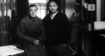 Movie still from “Zelig” (1983), directed by Woody Allen – Two men and a woman are standing in a room; Medium shot, Low angle