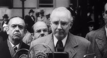 Movie still from “Zelig” (1983), directed by Woody Allen – An older man wearing a suit and tie in front of a crowd; Close Up shot, Low angle