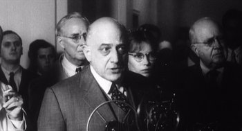 Movie still from “Zelig” (1983), directed by Woody Allen – A black - and - white photo of a man and two women; Medium shot, Low angle