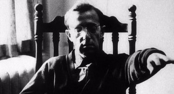 Movie still from “Zelig” (1983), directed by Woody Allen – A man sitting in a wooden chair in front of a window; Close Up shot, Low angle