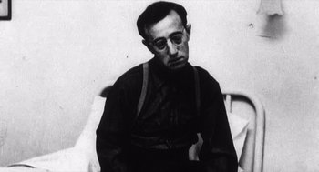 Movie still from “Zelig” (1983), directed by Woody Allen – An older man sitting in a chair wearing glasses; Close Up shot, Low angle