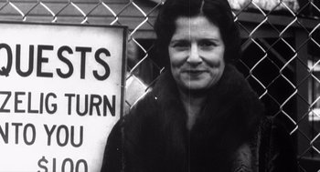 Movie still from “Zelig” (1983), directed by Woody Allen – An older woman standing in front of a sign; Medium shot, Low angle