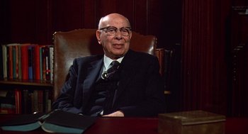 Movie still from “Zelig” (1983), directed by Woody Allen – An older man sitting in a chair in a room; Medium shot, Low angle