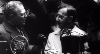 Movie still from “Zelig” (1983), directed by Woody Allen – A black - and - white photo of a man talking to another man; Medium shot, Low angle