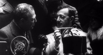 Movie still from “Zelig” (1983), directed by Woody Allen – A black - and - white photo of a man holding a camera; Close Up shot, High angle