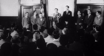Movie still from “Zelig” (1983), directed by Woody Allen – A group of men standing in front of an american flag; Wide shot, Low angle