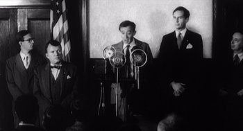 Movie still from “Zelig” (1983), directed by Woody Allen – A group of men standing next to each other in front of microphones; Medium shot, Low angle