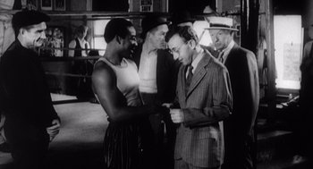 Movie still from “Zelig” (1983), directed by Woody Allen – A black and white photo of a man shaking hands with another man; Medium shot, Over the shoulder angle