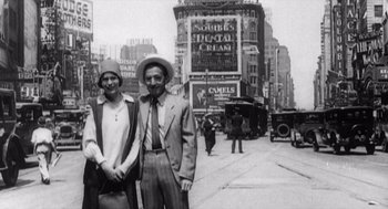 Movie still from “Zelig” (1983), directed by Woody Allen – An old photo of a man and a woman standing on the street; Wide shot, Low angle