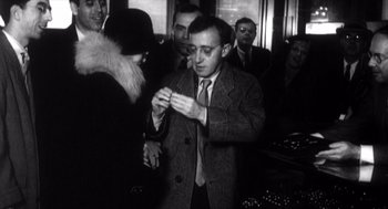 Movie still from “Zelig” (1983), directed by Woody Allen – A black and white photo of a man in a suit and tie; Medium shot, Over the shoulder angle