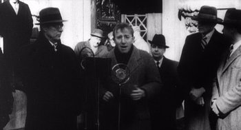 Movie still from “Zelig” (1983), directed by Woody Allen – An old black and white photo of a man speaking; Medium shot, Low angle