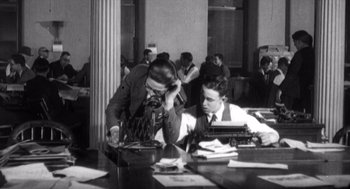 Movie still from “Zelig” (1983), directed by Woody Allen – Two men sitting at a table with a typewriter; Medium shot, High angle