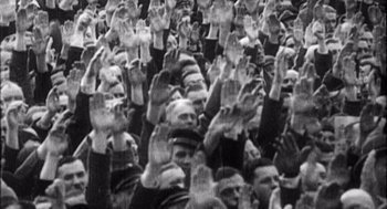 Movie still from “Zelig” (1983), directed by Woody Allen – A large group of people with their hands up in the air; Medium shot, High angle