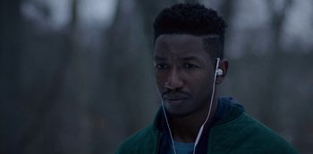 Movie still from “Archive 81” (2022), created by Rebecca Sonnenshine – A young man with headphones is listening to music; Close Up shot, Over the shoulder angle