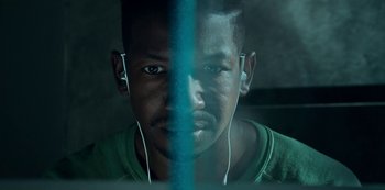 Movie still from “Archive 81” (2022), created by Rebecca Sonnenshine – A person wearing ear phones; Close Up shot, Low angle