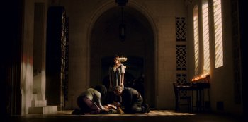 Movie still from “Archive 81” (2022), created by Rebecca Sonnenshine – A group of people sitting on the ground in front of a building; Wide shot, Low angle