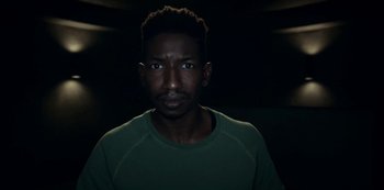 Movie still from “Archive 81” (2022), created by Rebecca Sonnenshine – A man in a green shirt is looking at the camera; Close Up shot, Low angle