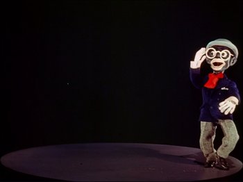 Movie still from “Ziegfeld Follies” (1945), directed by Roy Del Ruth – A person standing on a stage holding a camera in their hands; Medium shot, Low angle