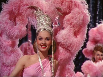 Movie still from “Ziegfeld Follies” (1945), directed by Roy Del Ruth – A woman in a pink dress and a feather headdress; Medium shot, Low angle