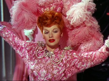 Movie still from “Ziegfeld Follies” (1945), directed by Roy Del Ruth – A woman in a pink dress and a pink feather headdress; Medium shot, Low angle