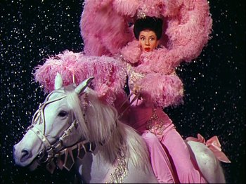 Movie still from “Ziegfeld Follies” (1945), directed by Roy Del Ruth – A woman dressed in pink riding on a white horse; Medium shot, High angle