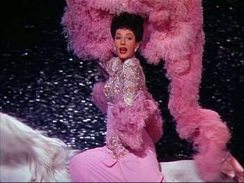 Movie still from “Ziegfeld Follies” (1945), directed by Roy Del Ruth – A woman in a pink dress and a pink feather boa; Medium shot, Low angle