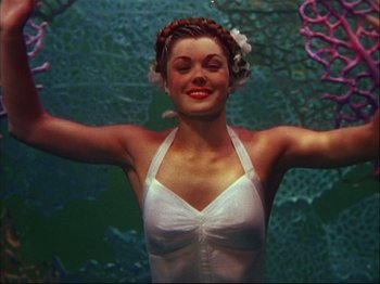 Movie still from “Ziegfeld Follies” (1945), directed by Roy Del Ruth – A woman in a bathing suit is standing in front of a fish tank; Medium shot, Low angle