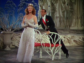 Movie still from “Ziegfeld Follies” (1945), directed by Roy Del Ruth – A man and a woman in formal wear sitting next to a bench; Medium shot, Low angle