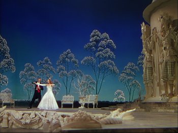 Movie still from “Ziegfeld Follies” (1945), directed by Roy Del Ruth – A couple dressed in wedding attire dancing in front of trees; Extreme Wide shot, Low angle
