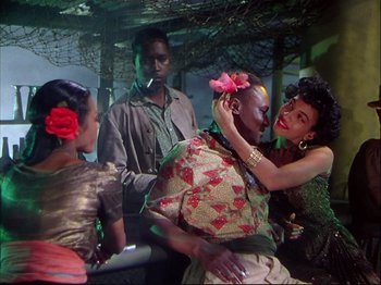 Movie still from “Ziegfeld Follies” (1945), directed by Roy Del Ruth – A group of people standing around a man with a flower in his hair; Medium shot, High angle