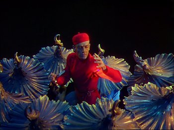Movie still from “Ziegfeld Follies” (1945), directed by Roy Del Ruth – A man in a red outfit sitting on a bunch of flowers; Medium shot, Low angle