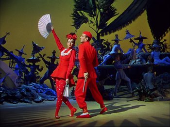 Movie still from “Ziegfeld Follies” (1945), directed by Roy Del Ruth – A man and a woman dressed in red and holding a fan; Wide shot, Low angle