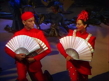 Movie still from “Ziegfeld Follies” (1945), directed by Roy Del Ruth – A couple of people that are standing up with fans; Medium shot, High angle
