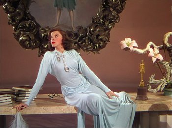 Movie still from “Ziegfeld Follies” (1945), directed by Roy Del Ruth – A woman sitting on top of a table in front of a mirror; Wide shot, Low angle