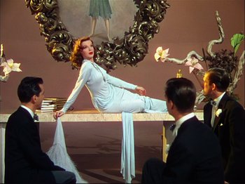 Movie still from “Ziegfeld Follies” (1945), directed by Roy Del Ruth – A woman sitting on top of a table next to a bunch of men; Wide shot, Low angle