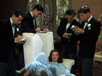 Movie still from “Ziegfeld Follies” (1945), directed by Roy Del Ruth – A group of men standing next to a woman; Medium shot, High angle