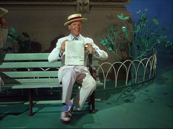 Movie still from “Ziegfeld Follies” (1945), directed by Roy Del Ruth – A man sitting on top of a wooden bench holding papers; Medium shot, Low angle