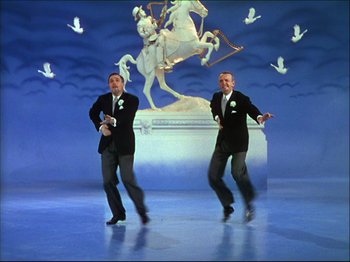Movie still from “Ziegfeld Follies” (1945), directed by Roy Del Ruth – A couple of men in black tuxedos dancing in front of a statue; Wide shot, Low angle