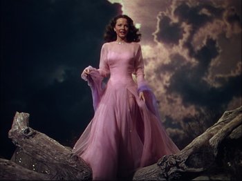 Movie still from “Ziegfeld Follies” (1945), directed by Roy Del Ruth – A woman in a pink dress standing on top of a tree; Wide shot, Low angle