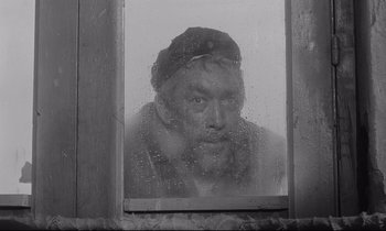 Movie still from “Zorba the Greek” (1964), directed by Michael Cacoyannis – A black and white photo of a man looking out of a window; Close Up shot, Over the shoulder angle