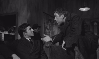 Movie still from “Zorba the Greek” (1964), directed by Michael Cacoyannis – Two men in suits and one man is pointing at another man in a suit; Medium shot, Over the shoulder angle