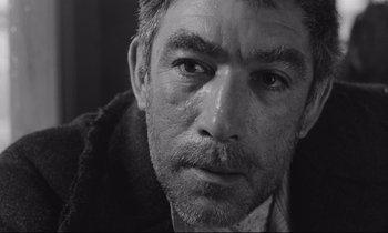 Movie still from “Zorba the Greek” (1964), directed by Michael Cacoyannis – Black and white photograph of a man's face; Close Up shot, Low angle