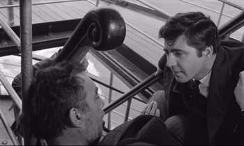 Movie still from “Zorba the Greek” (1964), directed by Michael Cacoyannis – Two men talking to each other while sitting in a chair; Medium shot, High angle