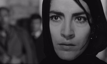 Movie still from “Zorba the Greek” (1964), directed by Michael Cacoyannis – A person wearing a hooded jacket; Close Up shot, Low angle